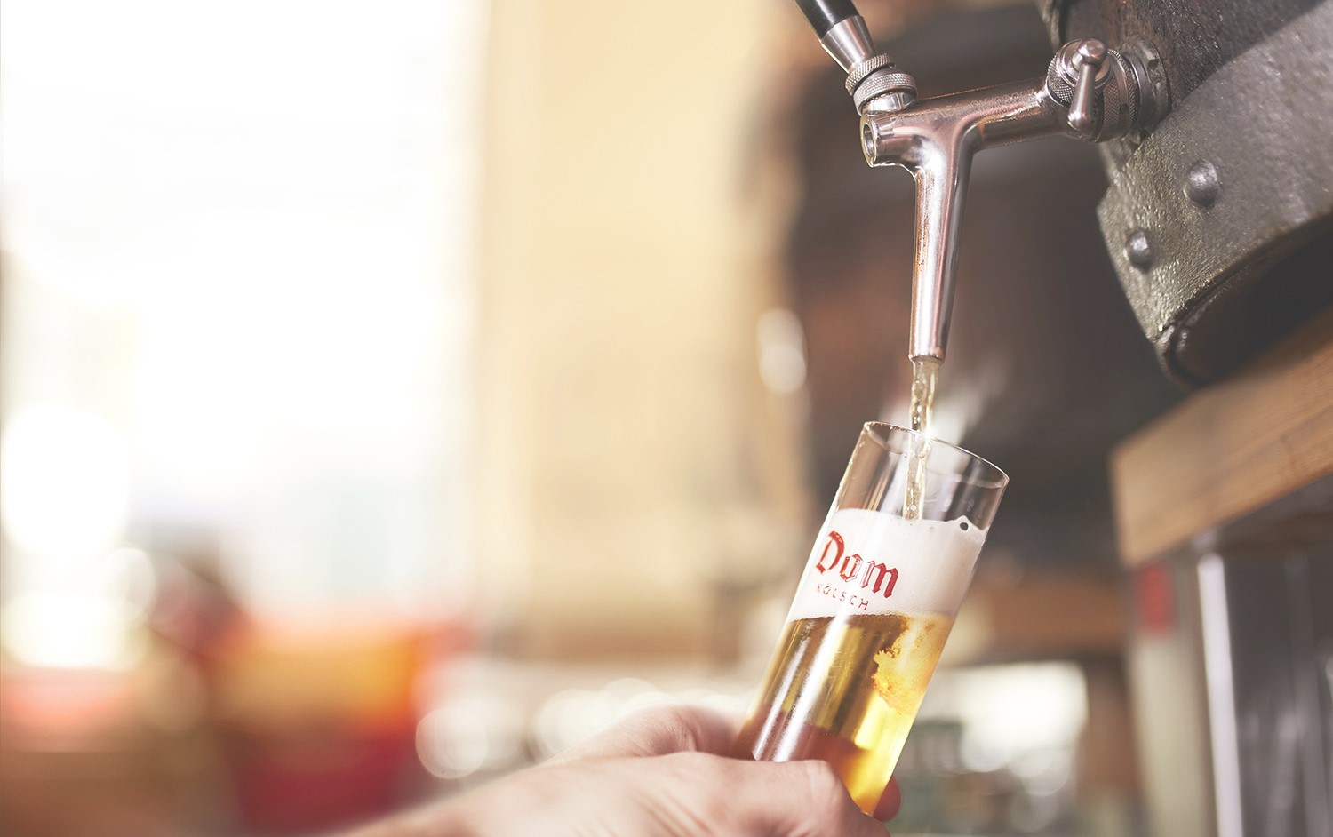 Eine Hand füllt ein Glas mit Bier aus einem Zapfhahn.